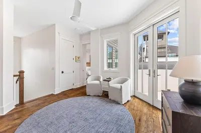 a white living room with two chairs and a table at Moonstruck Cottage and Carriage House in Rosemary Beach