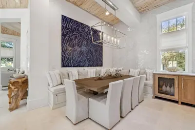 a dining room with a wooden table and white chairs at Moonstruck Cottage and Carriage House in Rosemary Beach