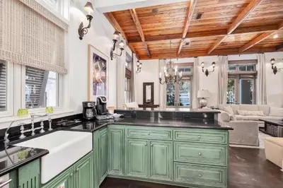 a kitchen with green cabinets and a living room at Joben Cottage in Rosemary Beach