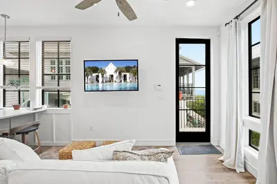 a white living room with a white couch and windows at Oasis Cottage & Carriage House in Rosemary Beach