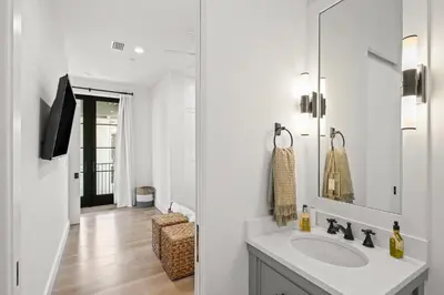 a white bathroom with a sink and a mirror at Oasis Cottage & Carriage House in Rosemary Beach