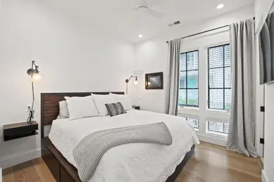 a white bedroom with a large bed and a window at Oasis Cottage & Carriage House in Rosemary Beach