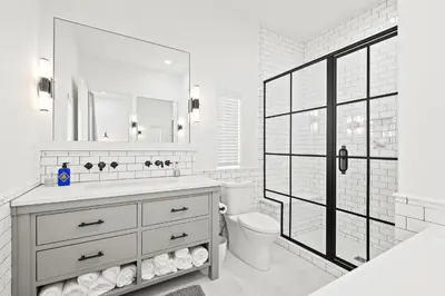 a white bathroom with a toilet and a sink at Oasis Cottage & Carriage House in Rosemary Beach