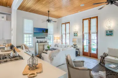 a living room with white furniture and a wooden ceiling at Uncorked Cottage in Rosemary Beach
