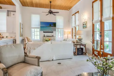 a living room with a large white couch and windows at Uncorked Cottage in Rosemary Beach