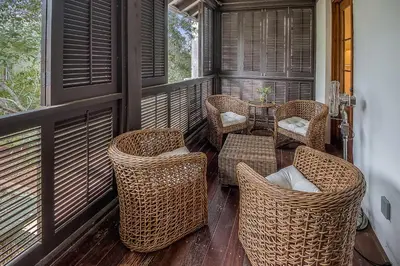 a screened porch with wicker chairs and a table at Uncorked Cottage in Rosemary Beach