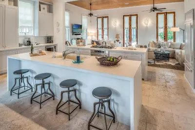 a kitchen with a island with three bar stools at Uncorked Cottage in Rosemary Beach