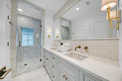 a white bathroom with a sink and a shower at Deauville Cottage in Rosemary Beach