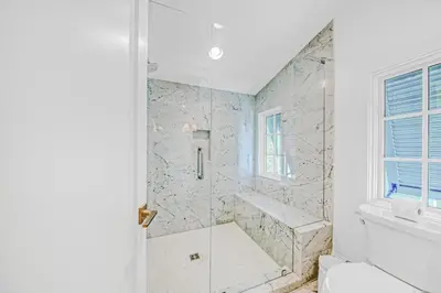 a white bathroom with a shower and a tub at Deauville Cottage in Rosemary Beach
