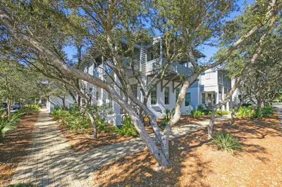 a white house with trees in front of it at Deauville Cottage in Rosemary Beach