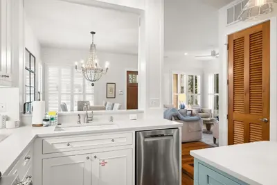a white kitchen with a sink and a mirror at R&B Cottage & Carriage House in Rosemary Beach