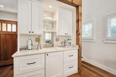 a kitchen with white cabinets and a sink at R&B Cottage & Carriage House in Rosemary Beach