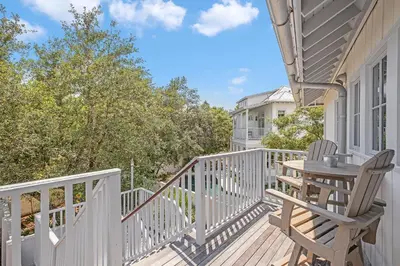 a deck with a table and chairs on a house at Butterfly Carriage House in Rosemary Beach