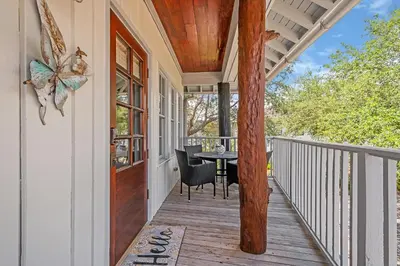a porch with a table and a glass door at Butterfly Carriage House in Rosemary Beach