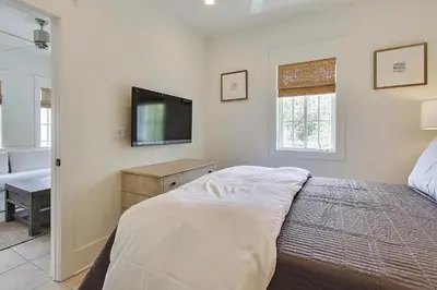 a bedroom with a bed and a flat screen tv at Southern Serenity Carriage House in Rosemary Beach