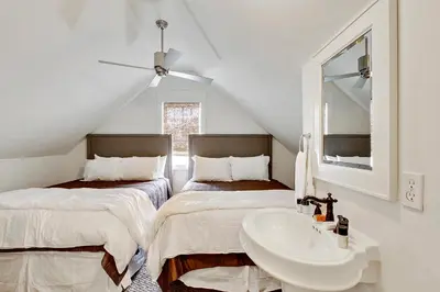 a attic bathroom with two beds and a sink at Southern Serenity Carriage House in Rosemary Beach