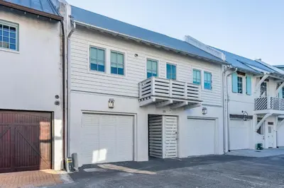 a white building with two garage doors and a balcony at Kidd Carriage House in Rosemary Beach