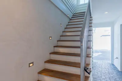 a staircase in a house with wooden floors and a glass railing at Kidd Carriage House in Rosemary Beach