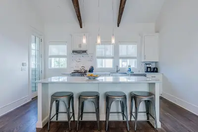a kitchen with a large white island with bar stools at Kidd Carriage House in Rosemary Beach