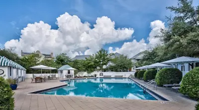 a swimming pool in a yard with chairs and umbrellas at Kidd Carriage House in Rosemary Beach