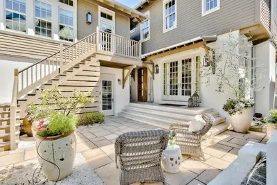 a home with a patio with chairs and stairs at Blue Heron Cottage & Carriage House in Rosemary Beach