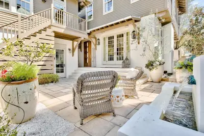 a patio with two wicker chairs and a fountain at Blue Heron Cottage & Carriage House in Rosemary Beach