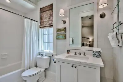 a bathroom with a toilet and a sink and a mirror at Blue Heron Cottage & Carriage House in Rosemary Beach
