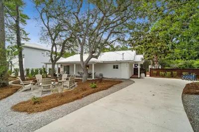 a white house with a tree and a patio at Moon Tide in Seacrest