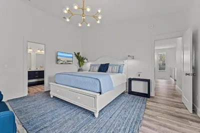 a white bedroom with a bed and a chandelier at Nashvilla in Seacrest
