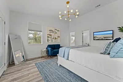 a bedroom with a large bed and a blue chair at Nashvilla in Seacrest
