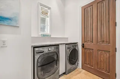 a laundry room with a washing machine and a door at Water Cottage and Carriage House in Rosemary Beach