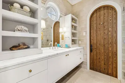 a bathroom with white cabinets and a wooden door at Water Cottage and Carriage House in Rosemary Beach