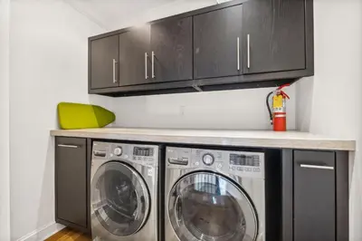 a laundry room with two washing machines and cabinets at Water Cottage and Carriage House in Rosemary Beach