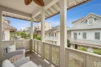 a balcony with chairs and a view of the street at Water Cottage and Carriage House in Rosemary Beach