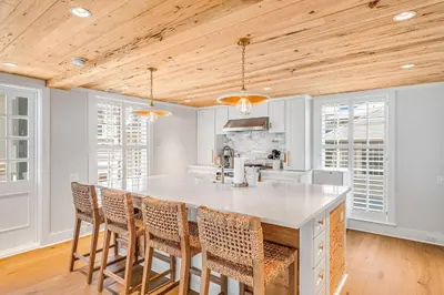 a kitchen with a large white island with chairs at Atwoods Cottage & Carriage House in Rosemary Beach