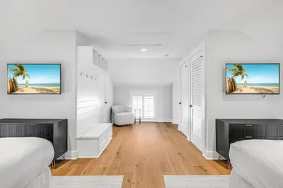 a white bedroom with two beds and a fireplace at Atwoods Cottage & Carriage House in Rosemary Beach