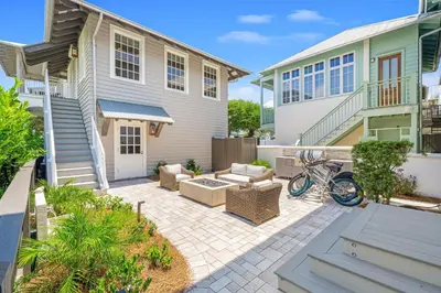 a patio with chairs and tables in front of a house at Atwoods Cottage & Carriage House in Rosemary Beach