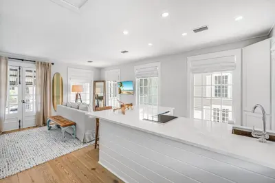 a kitchen with white countertops and a living room at Atwoods Cottage & Carriage House in Rosemary Beach