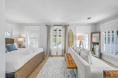 a white bedroom with a large bed and a couch at Atwoods Cottage & Carriage House in Rosemary Beach