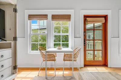a dining room with a table and chairs and windows at Hammock Carriage House in Rosemary Beach