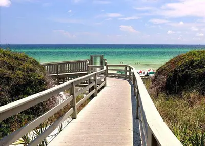 a wooden pathway to the beach with the ocean at Hammock Carriage House in Rosemary Beach