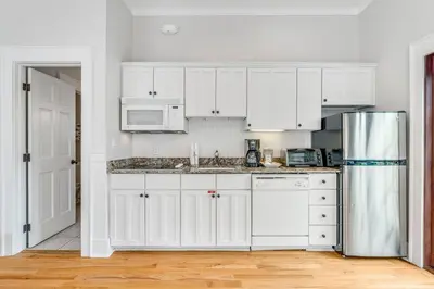 a kitchen with white cabinets and a refrigerator at Hammock Carriage House in Rosemary Beach