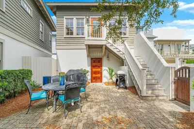 a patio with a table and chairs in front of a house at Hammock Carriage House in Rosemary Beach