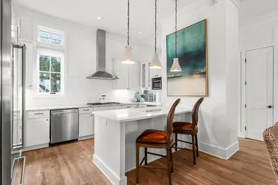 a kitchen with white cabinets and a table and chairs at Southern Seaside Cottage and Carriage House in Inlet Beach