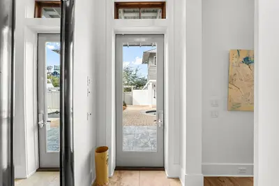 a hallway with white doors with a view of a yard at Southern Seaside Cottage and Carriage House in Inlet Beach