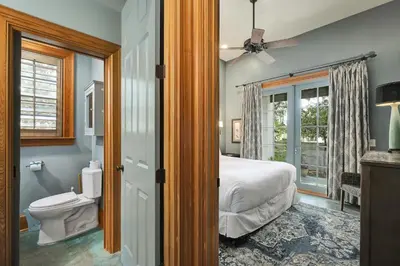 a bedroom with a bed and a toilet and a window at Villa Rose Cottage in Rosemary Beach