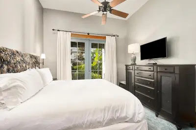 a bedroom with a white bed and a ceiling fan at Villa Rose Cottage in Rosemary Beach