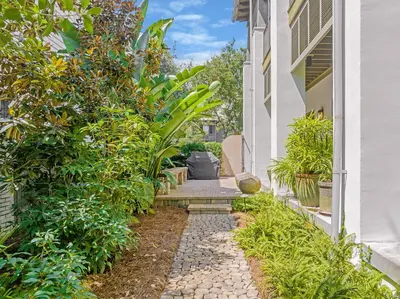 a garden path with plants and a building at Villa Rose Cottage in Rosemary Beach