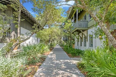 a sidewalk in front of a building with trees at Villa Rose Cottage in Rosemary Beach