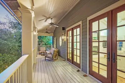 a front porch with a ceiling fan and glass doors at Hammock Cottage in Rosemary Beach